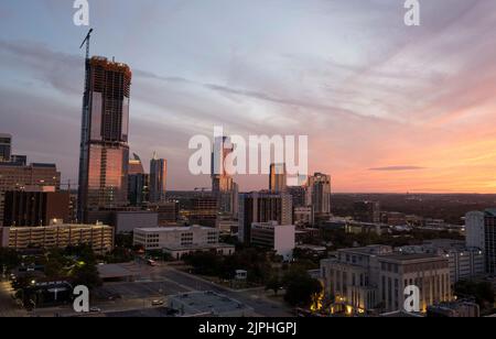 Die Skyline von Austin, Texas, die südwestlich vom Texas Capitol an einem warmen Sommerabend im August liegt. Das große Gebäude auf der linken Seite ist das Büro- und Wohngebäude von 6. und Guadalupe im Bau. Stockfoto