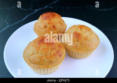 Ein Teller mit leckeren Bananenmuffins auf dem Tisch aus schwarzem Marmor Stockfoto