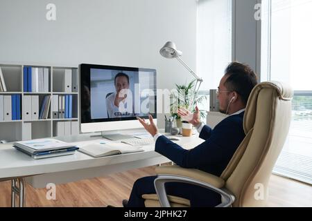 Asiatischer Unternehmer im Gespräch mit seinem Geschäftspartner per Videokonferenz Stockfoto