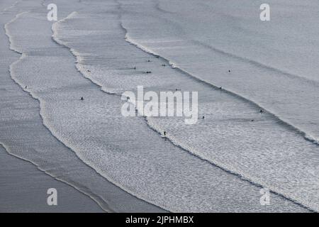 Surfer genießen das Wasser, während Wellen am Strand von Saunton Sands in Devon England Rollen Stockfoto