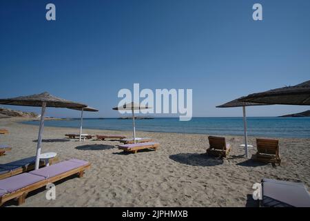 Leere Sonnenliegen und Sonnenschirme am herrlichen Strand von Manganari in iOS Griechenland Stockfoto