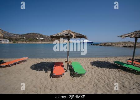 Leere Sonnenliegen und Sonnenschirme am herrlichen Strand von Manganari in iOS Griechenland Stockfoto