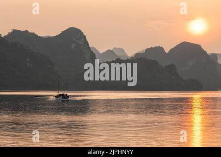 Sonnenuntergang in der Ha Long Bay mit Fischerboot auf der linken Seite Stockfoto