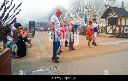 Menschen in einer Familiengruppe am Riesenrad an einem nebligen Sommertag in Scarborough, North Yorkshire Stockfoto