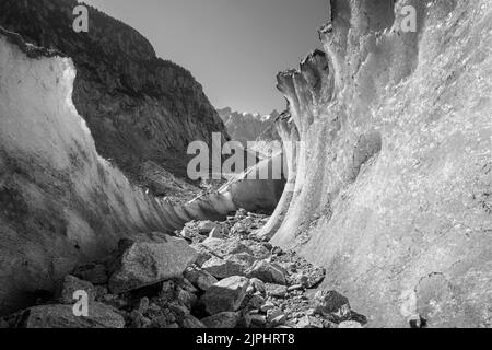 Die natürliche Gletscherhöhle der Gletscher Mer de Glace mit den Aiguilles Türmen im Hintergrund. Stockfoto