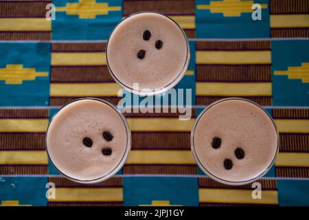 Flaches Lay-Foto von drei Cocktails im Dreieck auf dem Tisch mit einem bunten Tuch Stockfoto