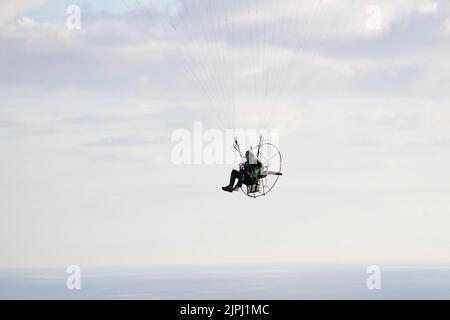 Ein Paramotor-Pilot, der nach einem Alleinflug über der Great Orme in Llandudno, Nordwales, an einem klaren und frühen Sommermorgen vor der Landung absteigt Stockfoto