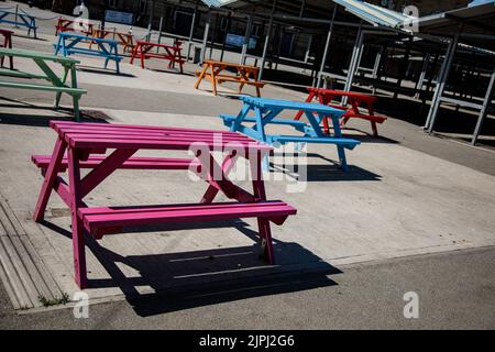 Bunte Picknickbänke auf einem Marktplatz an einem sonnigen Tag Stockfoto