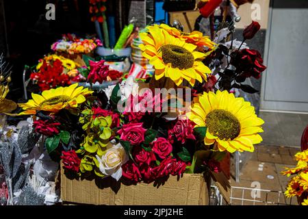 Gemischte künstliche Blumen draußen an einem schönen sonnigen Tag Stockfoto
