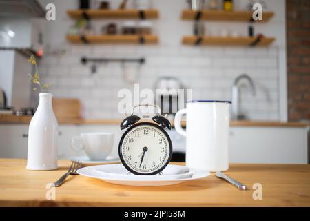 Wecker mit intermittierendem Fastenkonzept auf dem Küchentisch Stockfoto