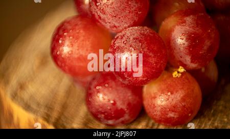 Trauben mit Wassertropfen auf einem natürlichen Holzbrett und natürlichem Abendlicht Stockfoto