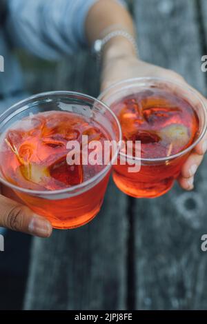 heers mit zwei aperol Spritz Cocktails in Plastikbechern Stockfoto