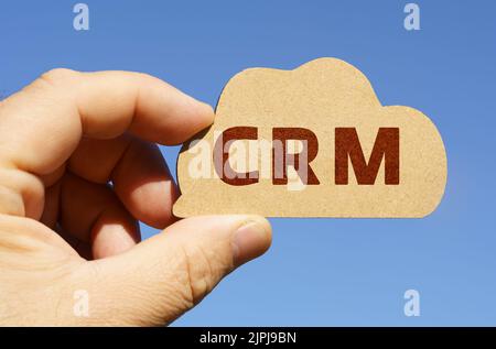 Vor dem Hintergrund des Himmels in den Händen eines Mannes, eine Figur einer Wolke mit der Aufschrift - CRM. Technologie- und Geschäftskonzept. Stockfoto