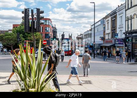 Menschen, die an der Fußgängerzone des Navigator Square, Holloway Road im Hintergrund, Islington, London, Großbritannien, vorbeigehen Stockfoto