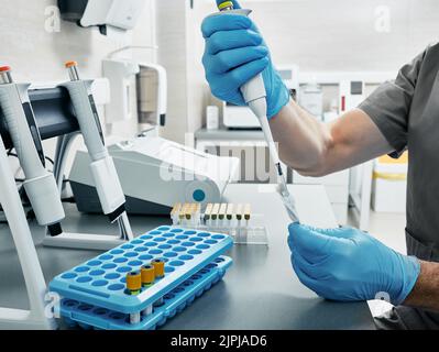 Wissenschaftler in Handschuhen und mit Mikropipette in den Händen im medizinischen Labor. Laborant bestimmt Blutgruppe und Rh-Faktor durch Gel-Agglut Stockfoto