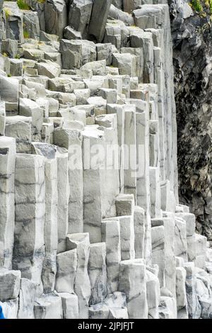 Vík í Mýrdal, Island - 3. Juli 2022 Nahaufnahme der beeindruckenden sechseckigen Basaltsäulen, die in der Nähe des schwarzen Sandstrandes Reynisfjara gefunden wurden. Stockfoto