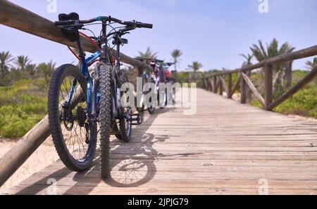 Detail der Fahrräder auf einem Holzsteg zum Strand geparkt Stockfoto