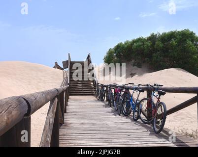 Detail der Fahrräder auf einem Holzsteg zum Strand geparkt Stockfoto