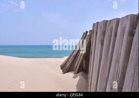 Detail eines Holzgeländers auf einer Düne mit dem Meer und dem Himmel im Hintergrund Stockfoto