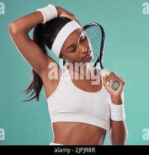 Tennisspieler dehnt den Hals zum Aufwärmen, bereitet die Muskeln vor und lockert sie für sportliche Leistungen vor grünem Studiohintergrund. Fit, aktiv und Stockfoto