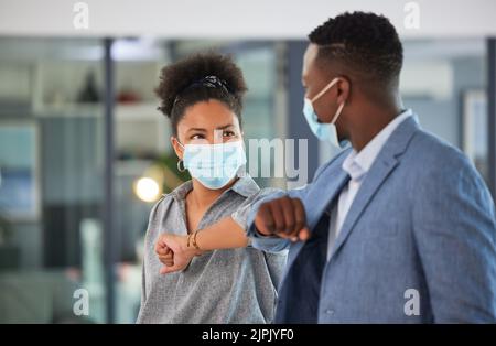 Covid, Kollegen und Begrüßung durch Berühren der Ellbogen und Tragen von Gesichtsmasken und sozialer Distanzierung in einem Büro. Freundliche und vielfältige Unternehmer Stockfoto