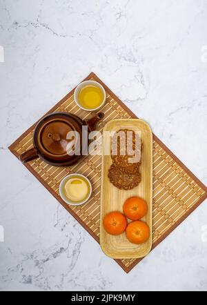 3 Mondkuchen und 3 Mandarinen werden mit chinesischem Tee serviert Stockfoto