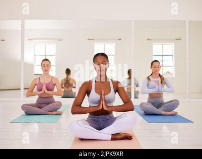 Meditieren, Yoga-Kurs oder Zen-Freunde sitzen zusammen im entspannenden, gesunden oder ruhigen Pilates-Studio. Verschiedene Gruppen von Yogi-Frauen und namaste Handmudra Stockfoto