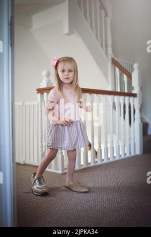 Lernen, sich selbst in die Schuhe von jemand Elsen zu stecken. Ein entzückendes kleines Mädchen, das in erwachsenen Schuhen durch das Haus läuft. Stockfoto