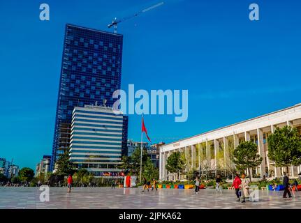 Eine Gruppe von Menschen, die auf dem Skanderbeg-Platz mit dem Operngebäude im Zentrum von Tirana, Albanien, spazieren gehen Stockfoto