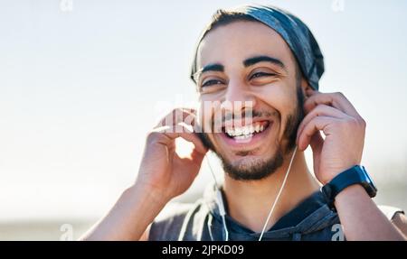 Ein sportlicher junger Mann, der Musik hört, während er im Freien trainiert. Stockfoto