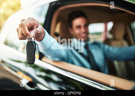 Ein Geschäftsmann, der die Schlüssel zu einem neuen Auto hält. Stockfoto