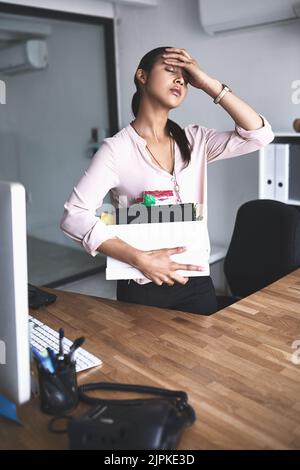 Was werde ich jetzt tun? Eine unglückliche Geschäftsfrau hält ihre Schachtel mit Habseligkeiten, nachdem sie von ihrem Job entlassen wurde. Stockfoto