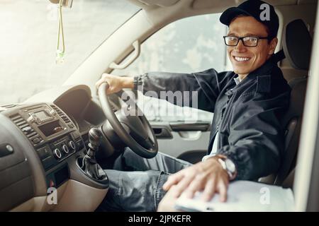 Es ist auf dem Weg zu Ihnen. Porträt eines Kuriers, der in seinem Lieferwagen Lieferungen macht. Stockfoto