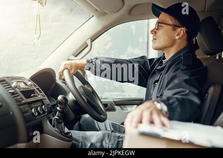 Die Lieferung hält an. Ein Kurier, der in seinem Lieferwagen Lieferungen macht. Stockfoto