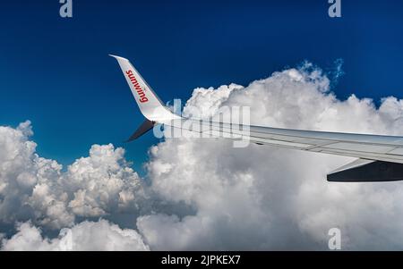 Rückkehr aus dem Urlaub in Holguin Kuba. Vor dem Hintergrund schwerer Wolken über dem Atlantik fliegt ein Sunwing-Flugzeug über die Küste Kubas. Stockfoto