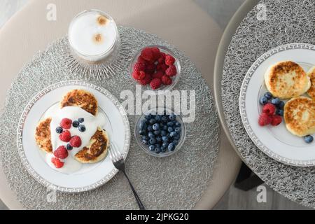 Blick von oben auf Hüttenkäse-Pfannkuchen mit Heidelbeeren und Himbeeren. Stockfoto