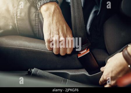 Sicherheit steht an erster Stelle. Nahaufnahme eines nicht erkennbaren Mannes, der seinen Sicherheitsgurt in einem Auto befestigt. Stockfoto