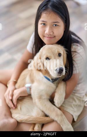 Porträt eines Mädchens mit einem goldenen Retriever-Welpen in ihrer Umarmung Stockfoto