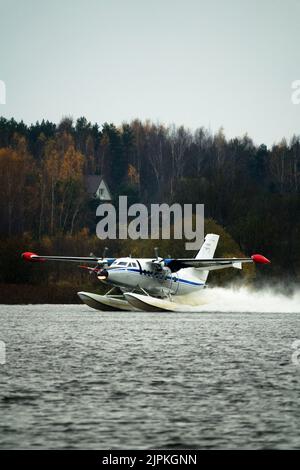 Das zweimotorige Wasserflugzeug ein Wasserflugzeug steigt aus dem Wasser, aus dem Waldsee, dem nördlichen Land auf. Wasserflugzeug Stockfoto