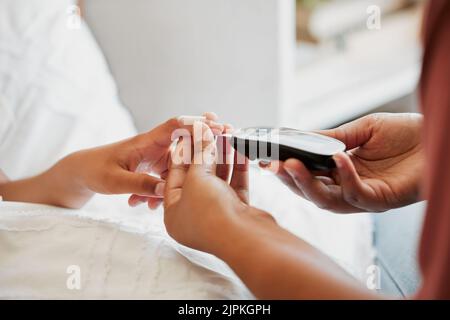 Diabetes, Gesundheitsfürsorge und ein Arzt, der den Zuckergehalt eines Kindes mit einem Blutzuckermessgerät in einem Krankenhaus überprüft. Krankenschwester mit einem digitalen Glukosimeter, Arzt Stockfoto