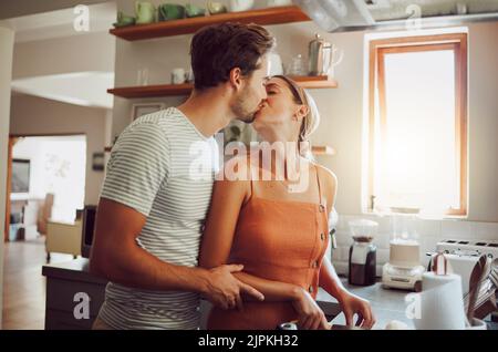 Romantisches Paar küsst, kocht und zeigt Zuneigung in der Liebe, während die Verbindung in einer Küche zu Hause. Fürsorglicher Freund und Freundin in einem Stockfoto