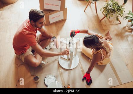 Recyceln, Sparsamkeit Möbel und Maler paar Malerei Holztisch für neue kreative Projekt in einer Wohnung. Oben Ansicht von Mann und Frau, die an arbeiten Stockfoto