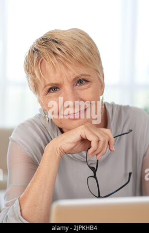 Porträt einer lächelnden, gealterten Geschäftsfrau mit Brille in der Hand Stockfoto