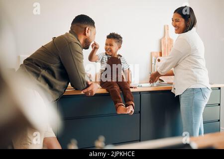 Eltern, Kind und Heim einer lustigen, liebevollen und fürsorglichen Familie, die mit ihrem Sohn verspielt ist. Lustige Vater machen dumme Gesichter mit seinem Jungen, während ein Stockfoto