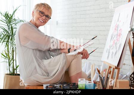 Porträt einer glücklichen, kreativen älteren Frau in ihrem Heimstudio Stockfoto