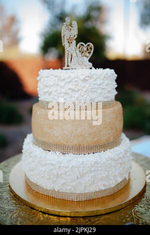 Weiße und goldene Hochzeitstorte mit Figuren und Rippensteinen. Stockfoto