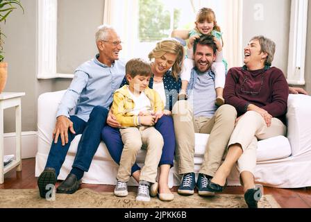 Die Freude der Familie erfüllt die Welt mit Liebe. Eine Familie mit mehreren Generationen, die zu Hause auf dem Sofa sitzt. Stockfoto