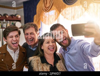 Lustige Gesichter mit der Familie machen. Eine Familie, die zu Hause ein Selfie macht. Stockfoto