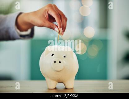 . Sparen und Investitionen für die Zukunft, Hand, eine Münze in eine Sparschwein, Geldwachstum und finanzielle Freiheit. Altersvorsorge, Versicherung und Budget Stockfoto