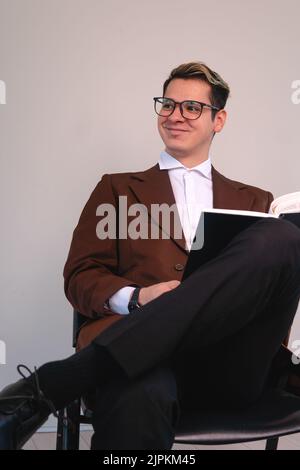 Ein College-Professor in einem Anzug, der lächelnd sitzt. Glücklicher Anwalt auf weißem Hintergrund. Ein Geschäftsmann mit einem erfreulicher Ausdruck. Eleganter lächelnder Mann. Hochwertige Fotos Stockfoto